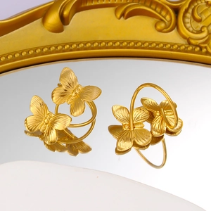 Detail of 18K gold butterfly rings with textured wings on a reflective mirror surface