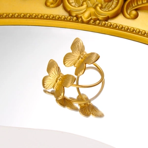 Macro detail of golden double butterfly ring with brushed metal texture and 18K finish