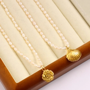 Detailaufnahme von 18K Gold Rosen- und Muschelanhängern an einer Perlenhalskette