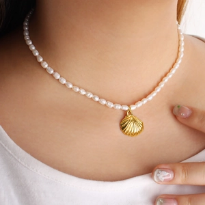 Französische Perlenkette mit goldenem Muschelanhänger am Hals für elegantes Geschenk