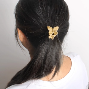 Détail d'un élastique à cheveux papillon doré vintage sur une coiffure en queue de cheval