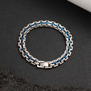 Vue macro d'un bracelet à maillons en acier bicolore sur fond de cuir texturé noir