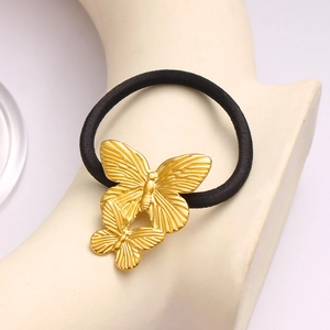 Vue détaillée des breloques papillon dorées sur un élastique à cheveux noir