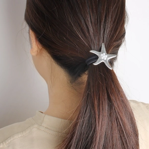 Détail de l'élastique à cheveux avec étoile de mer argentée et perles élégantes