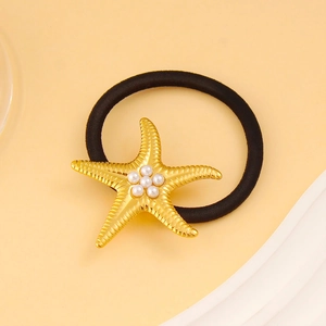Détail de l'élastique à cheveux étoile de mer dorée avec perles sur fond jaune