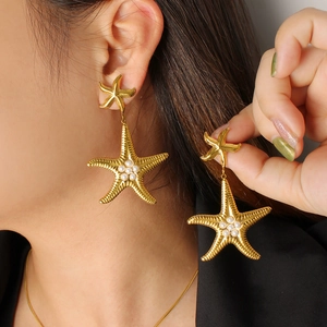 Dettaglio di orecchini a stella marina in oro 18K con texture a raggiera e perle