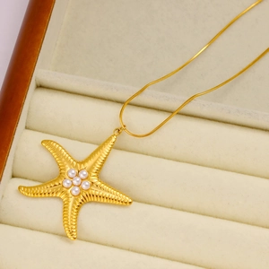 Dettaglio macro di una collana a stella marina dorata con sei perle in scatola