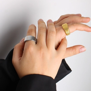 Detailed view of wide titanium steel rings featuring vertical stripes in gold and silver finish