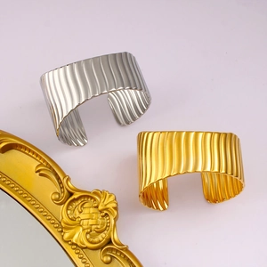 Détail des bracelets ouverts or et argent avec texture ondulée verticale et fini brillant