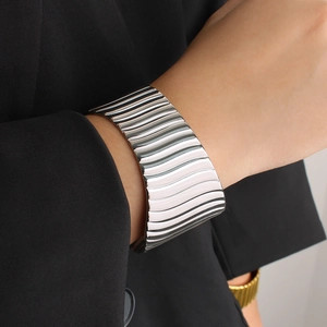 Détail d'un large bracelet manchette métallique à texture ondulée verticale élégante
