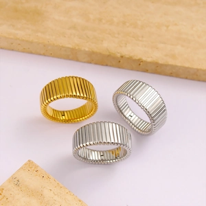Detailed view of three striped stainless steel rings in gold and silver on stone