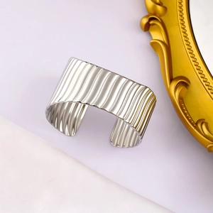 Détail d'un bracelet ouvert argenté avec texture à rayures verticales et fini métallique