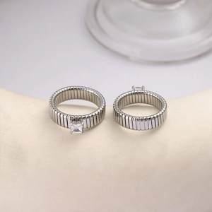 Close-up of silver steel watch-band style rings with a square cubic zirconia stone