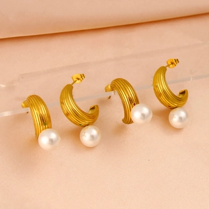 Detail of C-shaped gold-tone textured earrings with pearls and red green gemstones