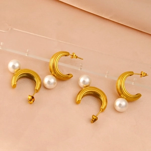 Detail showing gold C-shaped hoop earrings with vertical texture and white pearls
