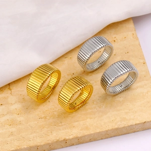 Minimalist wide Tubogas stripe rings in gold and silver on marble stone background