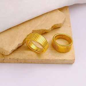 Detail shot of golden Tubogas ribbed rings on elegant stone and white fabric