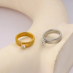 Detail of ribbed 18K gold and silver rings with square zircon stones on ceramic base