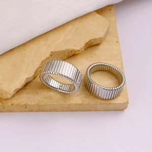 Macro detail of silver striped textured stainless steel rings on a stone surface