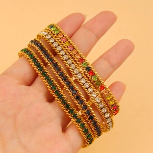 Détail de quatre bracelets dorés ornés de pierres de zircon colorées et vibrantes