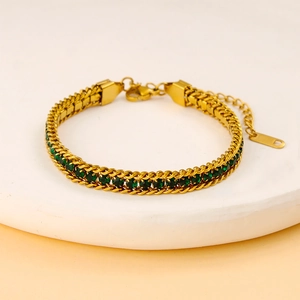 Détail d'un bracelet en chaîne dorée orné de pierres de zircon de couleur vert émeraude