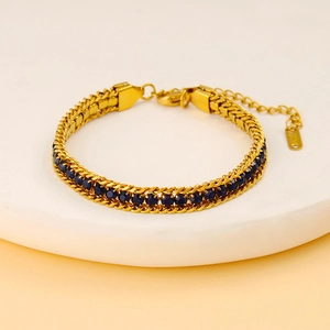 Détails de gourmette tressée dorée avec incrustation de zircons ronds bleu foncé
