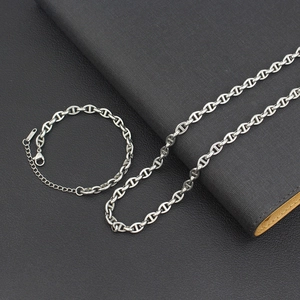 Detailed close-up of silver mariner chain necklace and bracelet set on leather
