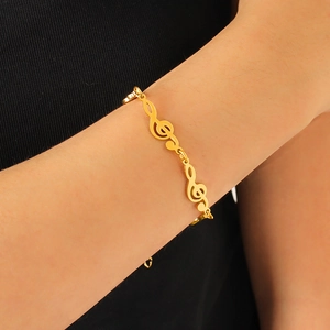 Detail of a 18K gold plated stainless steel bracelet featuring treble clef musical notes