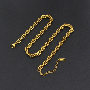 Close-up of golden stainless steel pig nose chain necklace on black leather surface