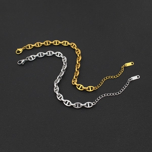 Detail of gold and silver anchor link bracelets with 18KGP stamp on black leather surface