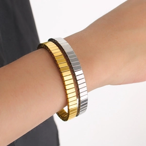 Gros plan de bracelets extensibles dorés et argentés à texture verticale au poignet