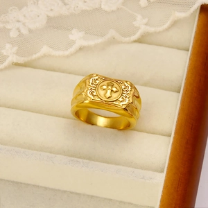 Close-up of golden stainless steel ring featuring relief cross and vintage scroll engraving