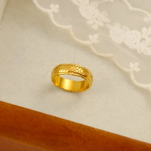 Detailed close-up of 18K gold plated ring with vintage floral engraving on white lace