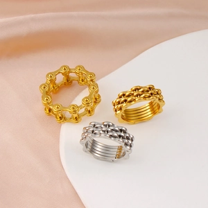 Detail view of 18K gold and silver plated chain-link gear rings on white display board