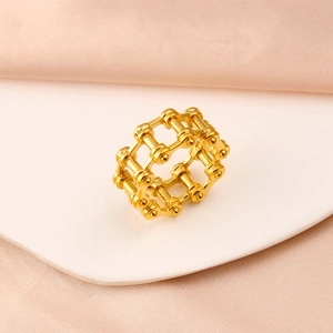 Detailed view of the gold bicycle chain link ring on a soft satin fabric background