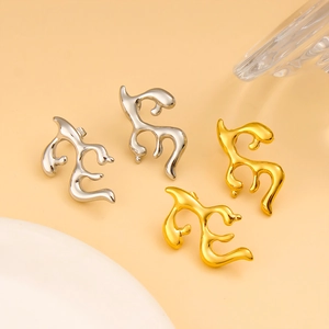 Close-up of stylish 18K gold and silver antler earrings on a beige background