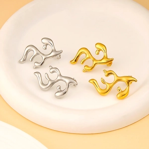 Polished 18K gold and silver antler-shaped titanium earrings on a white stone display