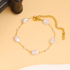 Detalle de una elegante pulsera de cadena dorada con perlas irregulares y cierre de mosquetón