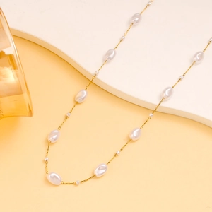 Elegante collar de cadena dorada con perlas barrocas en un soporte minimalista