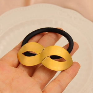 Detail of high-elasticity black hair tie with a matte gold number 8 metal ornament