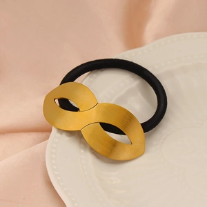 Macro view of gold infinity metal accent on high elasticity black hair tie on silk
