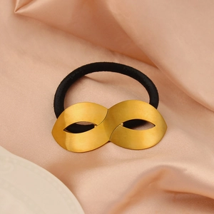 Detailed macro view of black elastic hair tie with matte gold metal figure-eight ornament