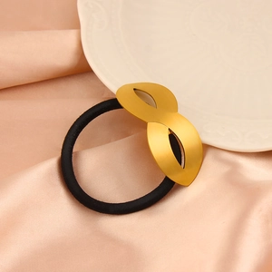 Close-up of golden matte metal ornament on a high-elastic black hair tie over silk fabric