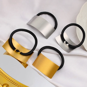 Detail of four brushed gold and silver metal hair ties on elegant white silk background