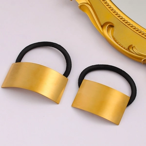 Minimalist rectangular gold brushed metal ponytail cuff holder on pink surface
