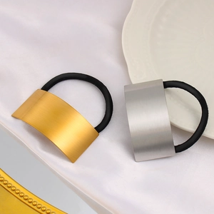 Close-up of gold and silver brushed metal arc hair ties on white silk fabric background