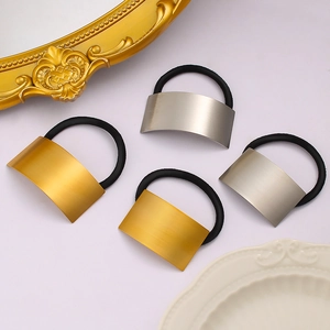 Detail of four metal elastic hair ties in gold and silver with a brushed finish