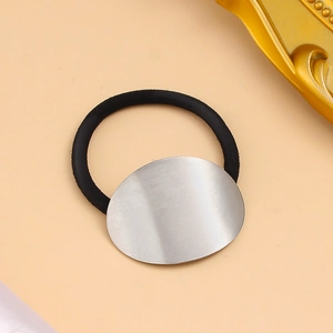 Détail de la boucle ovale en métal brossé argenté sur un élastique noir pour queue de cheval
