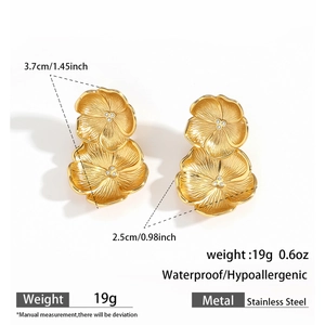 Vue détaillée de boucles d'oreilles fleur en acier doré avec pétales superposés et cristaux