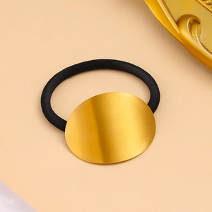 Détail d'un élastique cheveux ovale en métal doré avec une texture brossée raffinée